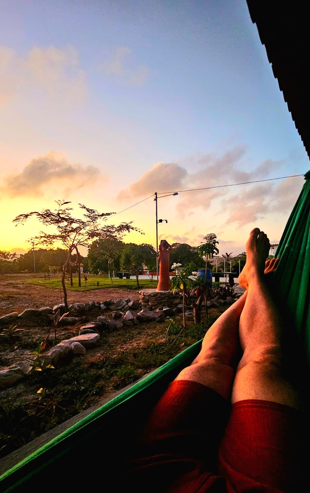 Pôr do sol alaranjado visto de dentro de uma rede no Chalés da Ribeira